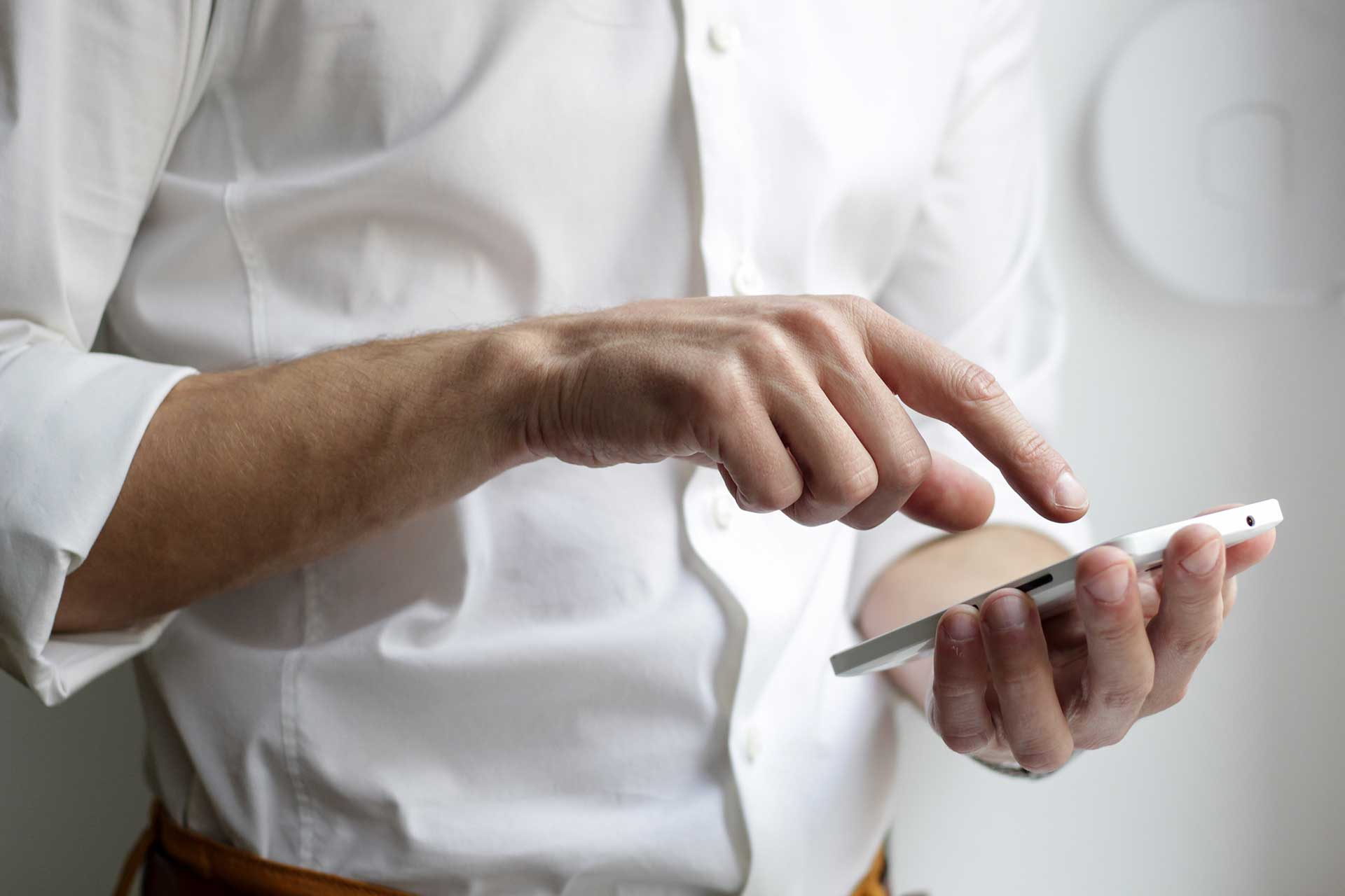 Man in white shirt using phone to optimize his Google My Business listing for dentists